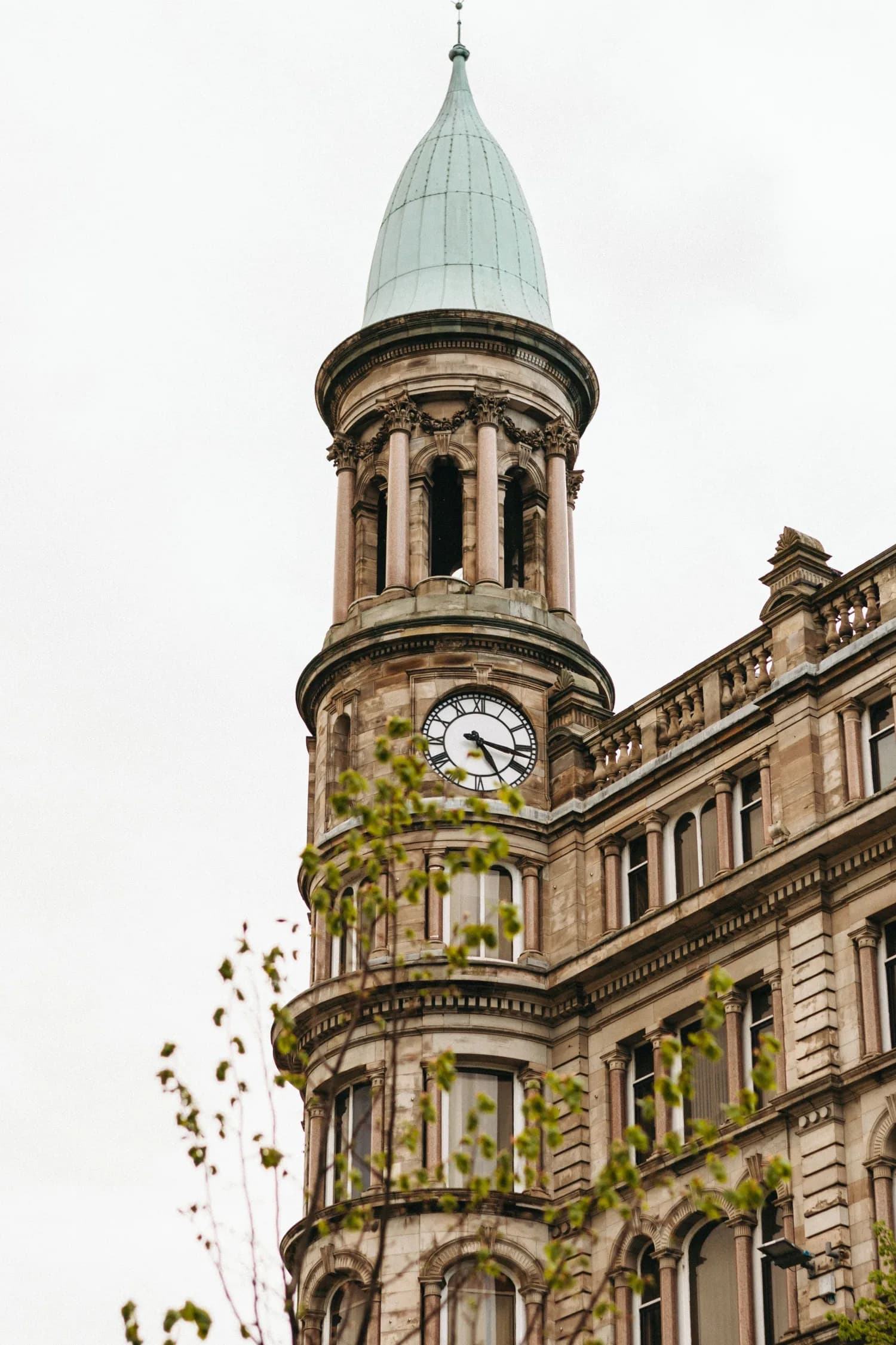 A historic Glasgow clock tower with a pale copper spire